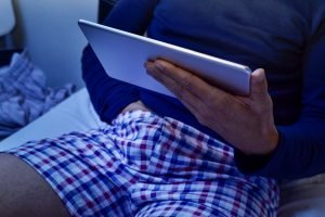 man with his hand under his underware while is watching his tablet
