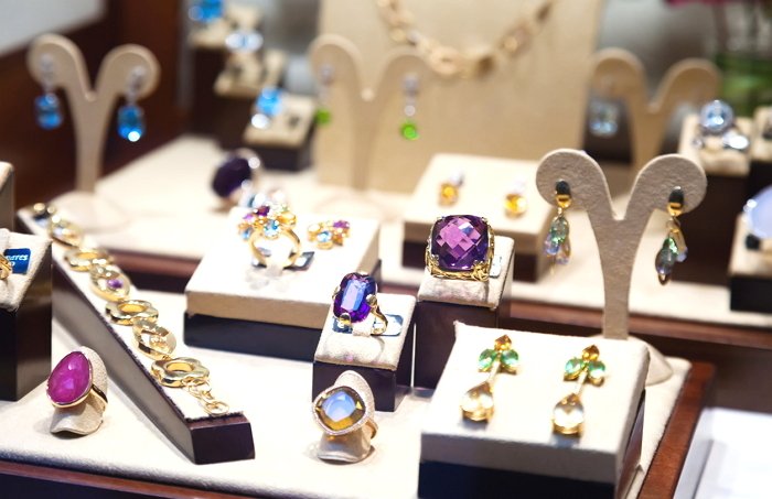Gold jewelry with gems at showcase of jewelry shop