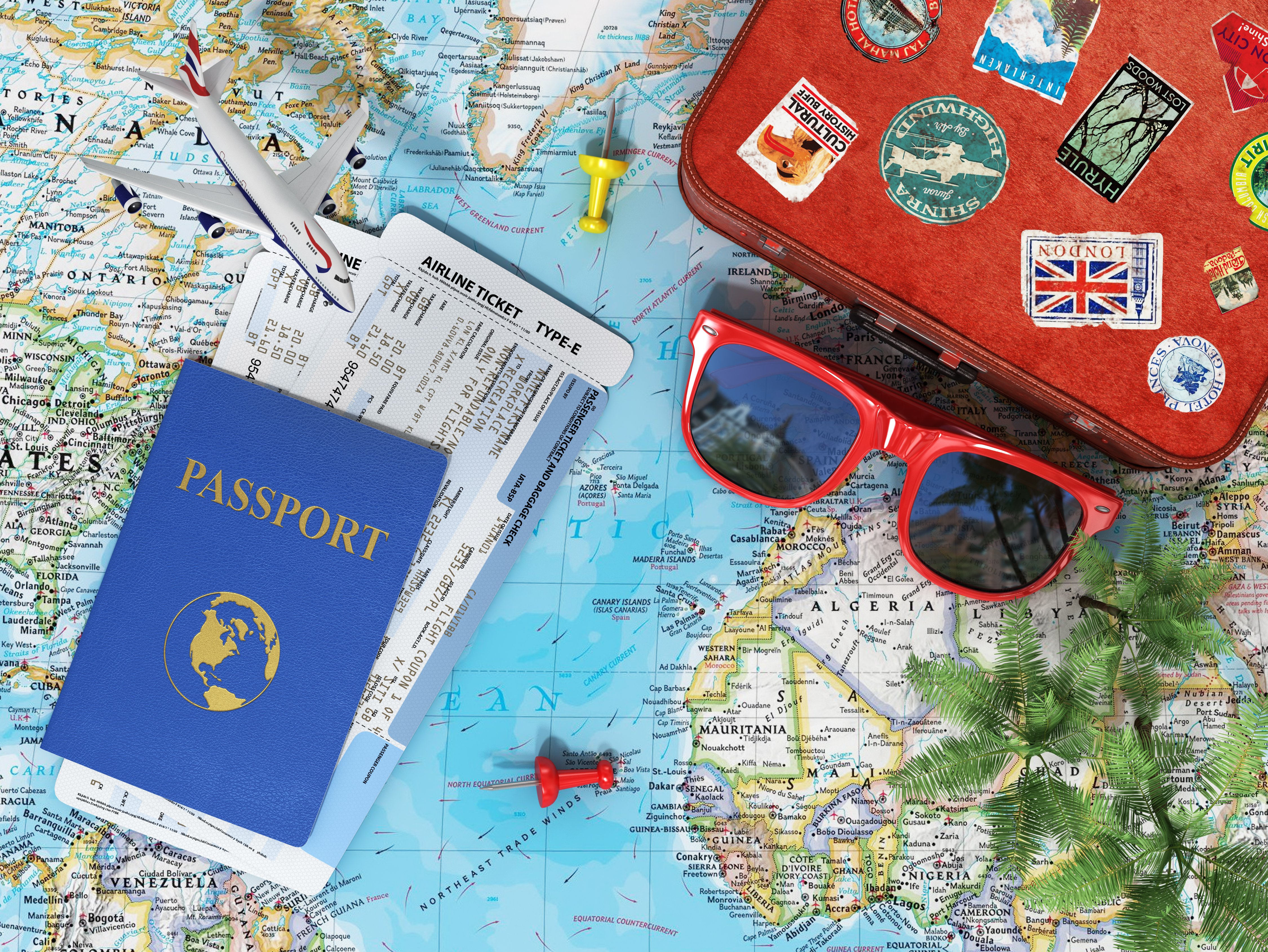 Recreation and travel concept. Old suitcase for travel, plane, sunglasses, passport with air tickets and palms on the world map and blue sky.