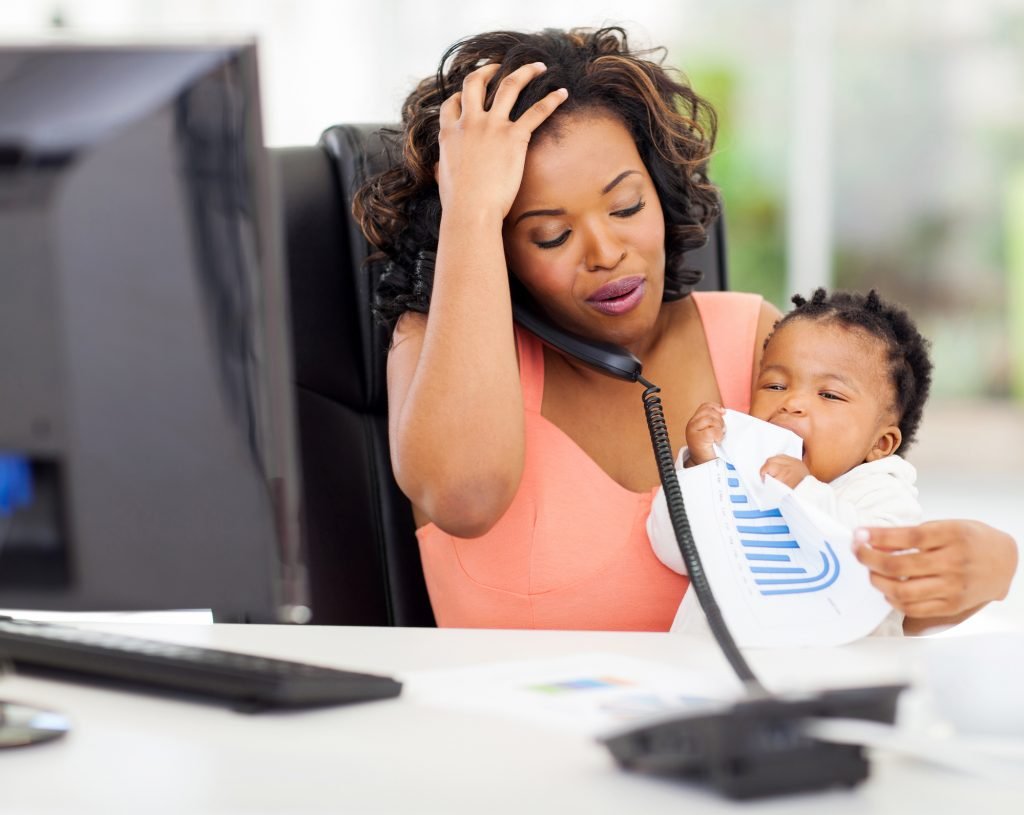 stressed african american businesswoman with baby girl in office