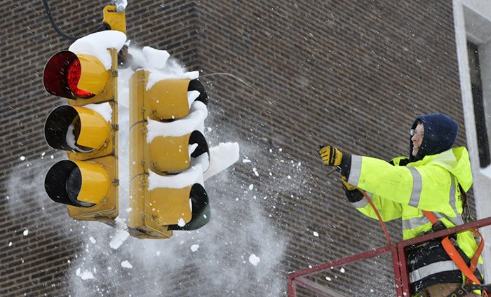 City Of Erie Traffic Engineering Employee Uses Compressed Air To Clear Snow From A Traffic Signal