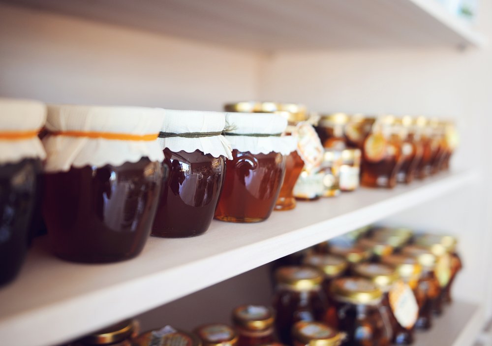 Assorted honey and jams in glass jars on a shelf