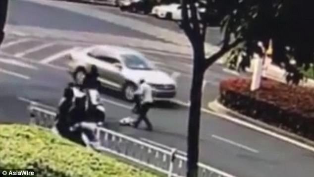 One female onlooker walks past and picks up the baby before other vehicles drive past