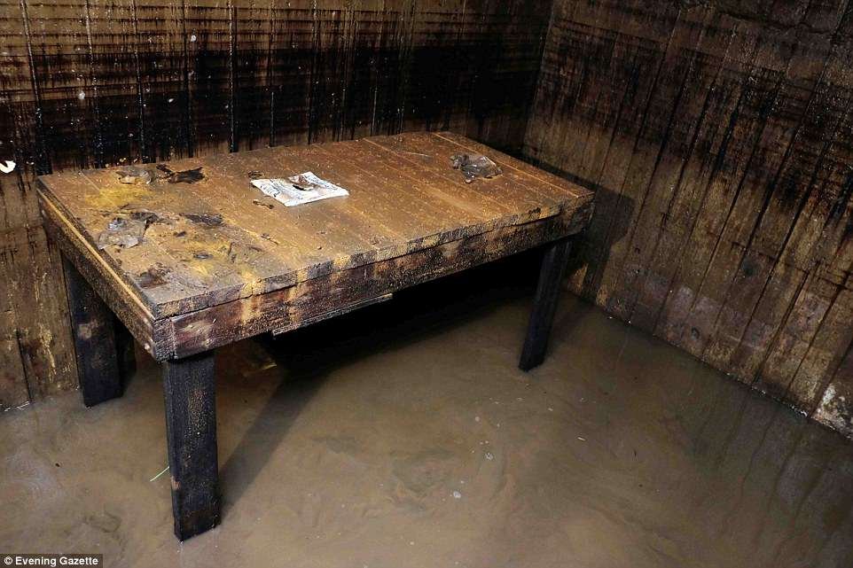 A wooden table has been left blackened but remains upright despite being submerged in water for a number of years in the underground bunker