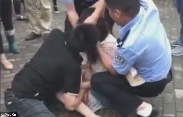 Polícia tenta separar o jovem chora de dor enquanto os espectadores estão assistindo
