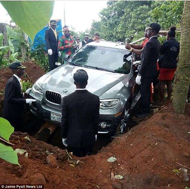 A remarkable photo taken at the funeral shows pall bearers lowering the enormous SUV into the vast grave