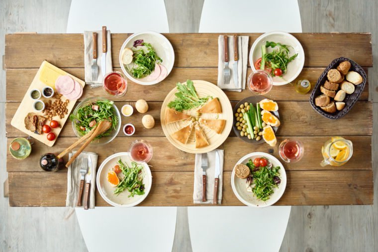 Above view of dinner table with delicious food set for four in cafe or restaurant