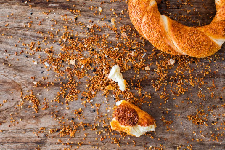 Turkish bagel simit pieces and sesame seeds crumb on wooden background