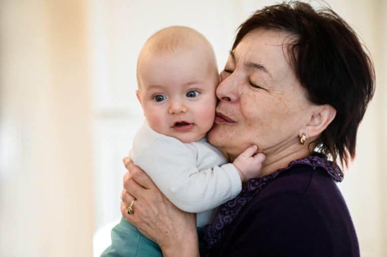 Grandmother is kissing her baby grandson - indoors scene