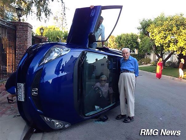 Couple de personnes âgées posant pour une photo après le renversement de leur voiture (la femme est toujours coincée à l'intérieur)