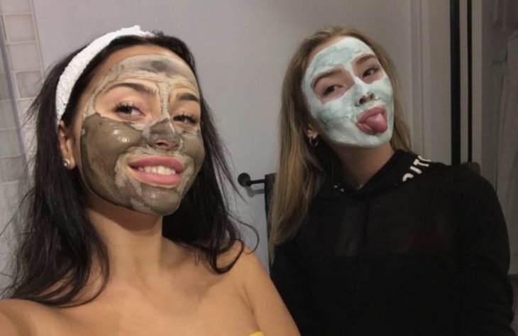 Amigas dentro de un baño tomando selfies y usando mascarillas faciales 