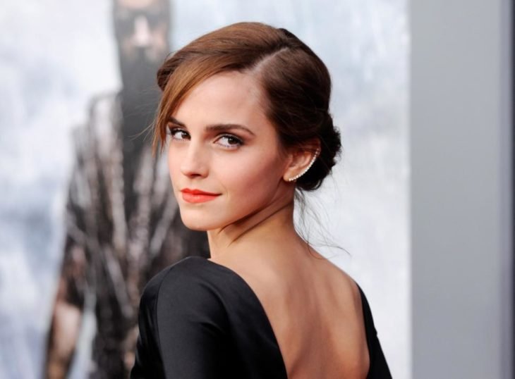 Emma Watson de espaldas, girando de perfil mostrando su vestido negro