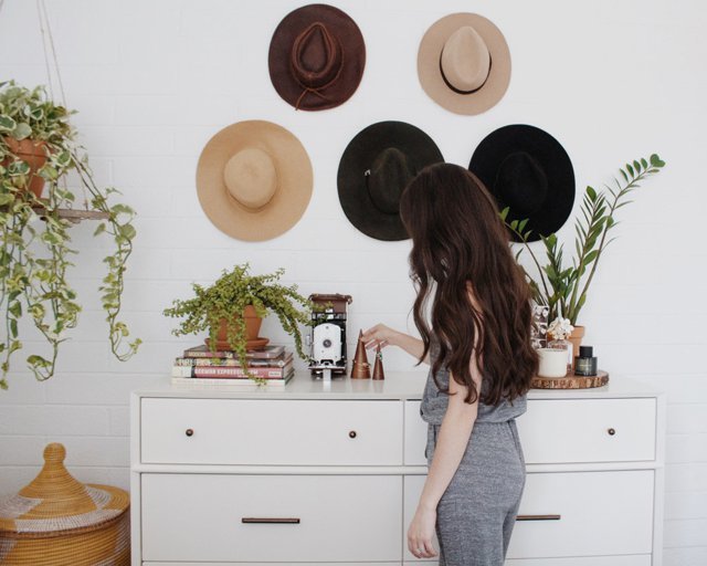 Mujer viendo sombreeros coldados en la pared como decoración