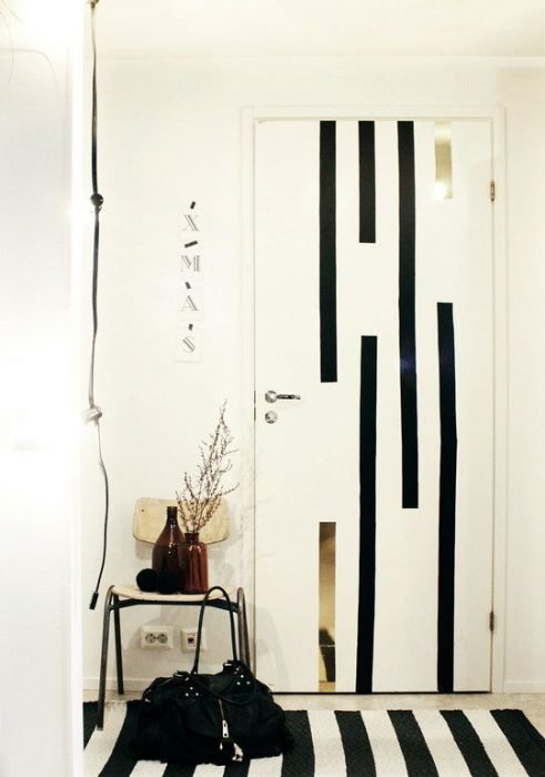 Puerta de una habitación decorada con líneas de color negras que combinan con la alfombra de la habitación 