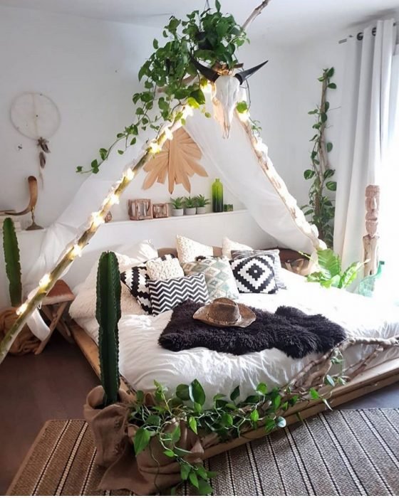 Habitación decorada con un tipi en el centro de la cama y sobre él se encuentran plantas verdes que ayudan a decorar el espacio en blanco 