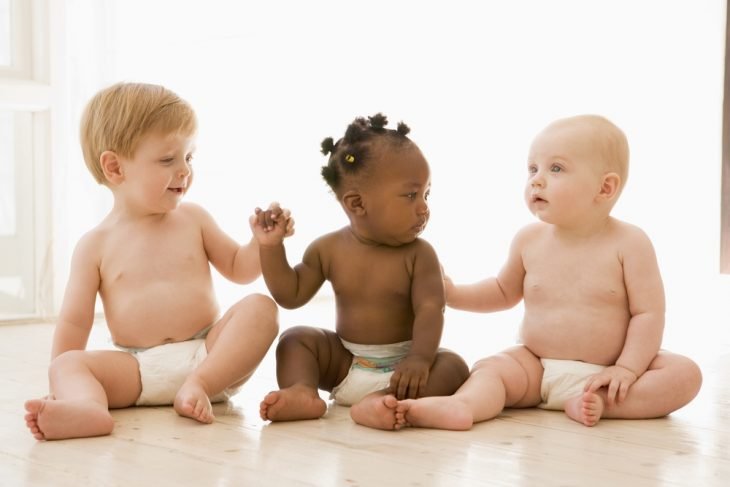 Bebés de diferentes razas viéndose sentados entre sí