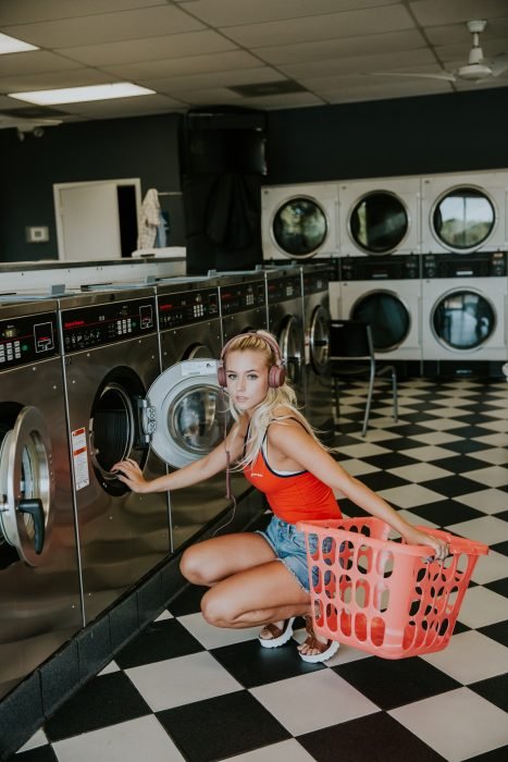 Mujer rubia en una lavandería lavando su ropa sucia