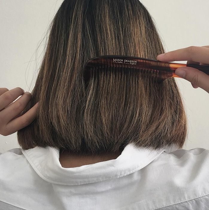 Chica peinándose el cabello con corte de hongo