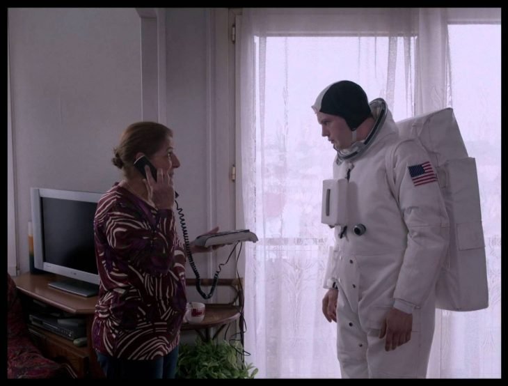 una señora con un teléfono en la oreja al lado de un joven vestido de astronauta 