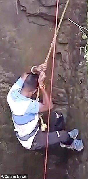 Govind Solanki, a volunteer with Wild and Street Animal Rescue Society in India, climbs down to save the snake