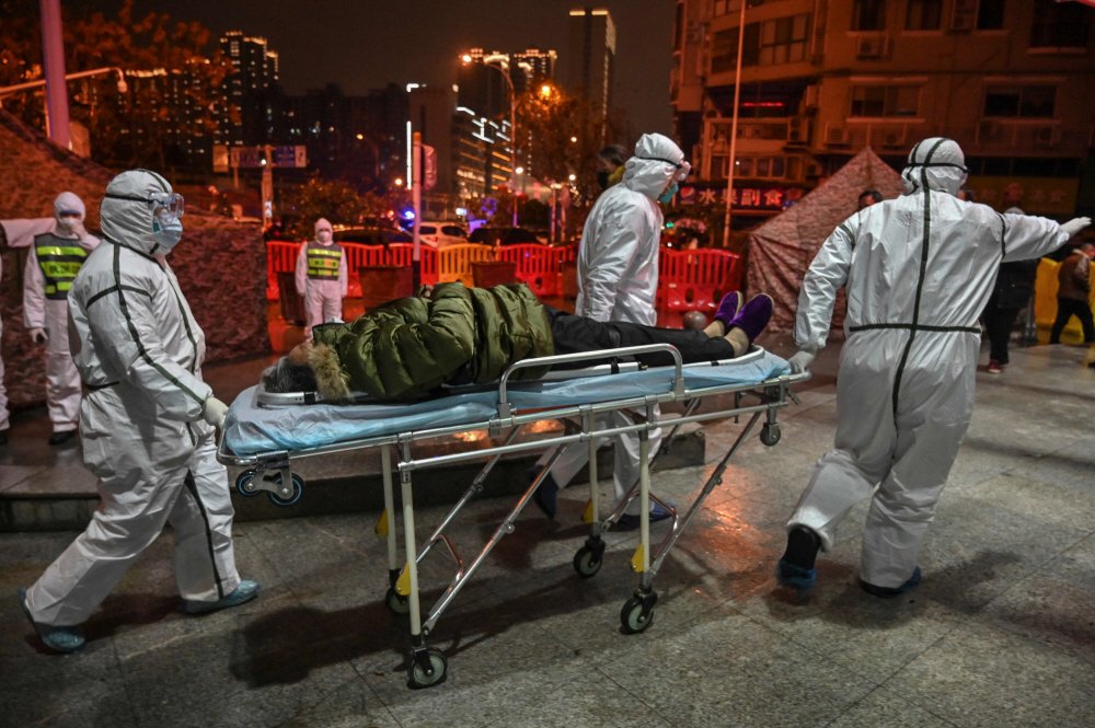 25일(현지시간) 신종코로나바이러스가 처음 발생한 중국 우한시의 적십자사 병원에서 방역복을 입은 의료진들이 감염된 것으로 추정되는 환자를 긴급히 이송하고 있다.  [AFP = 연합뉴스]