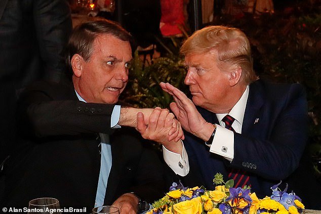 President Donald Trump shaking hands with Brazilian President Jair Bolsonaro during a dinner at Mar-a-Lago on Saturday night; Bolsonaro has tested positive for coronavirus