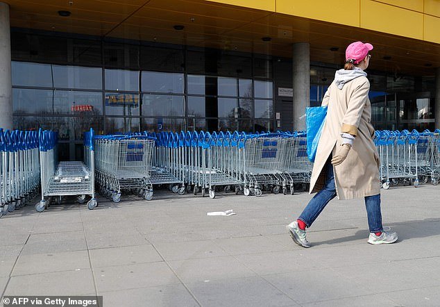 A woman walks past by shopping trolleys in front of a closed Ikea store in Berlin today