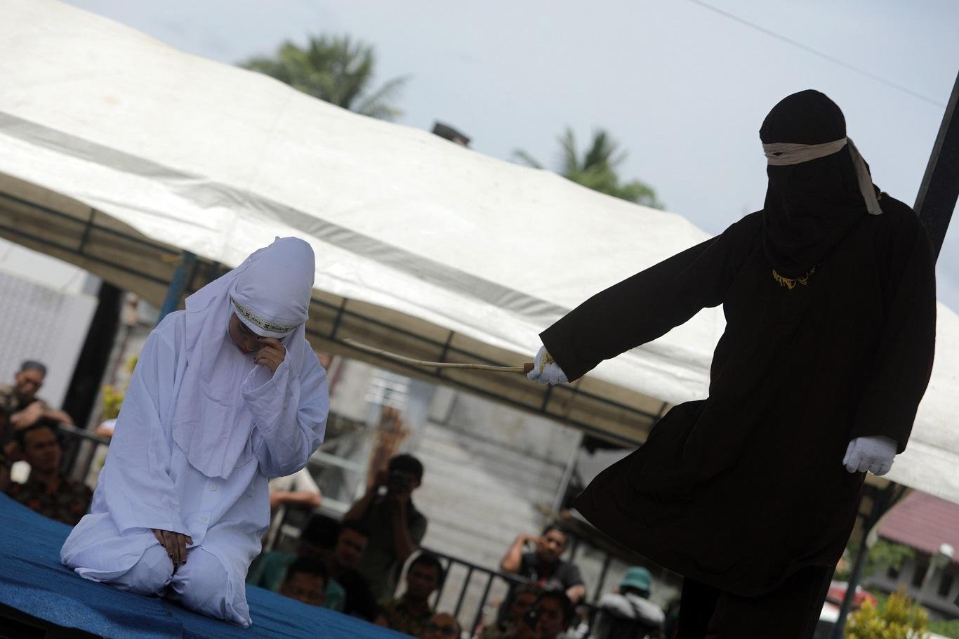 Una mujer de confesión musulmana recibe públicamente azotes con una vara de madera como parte del castigo por romper la ley "sharía" o islámica, que prohíbe mantener relaciones extramaritales. (Foto: EFE)