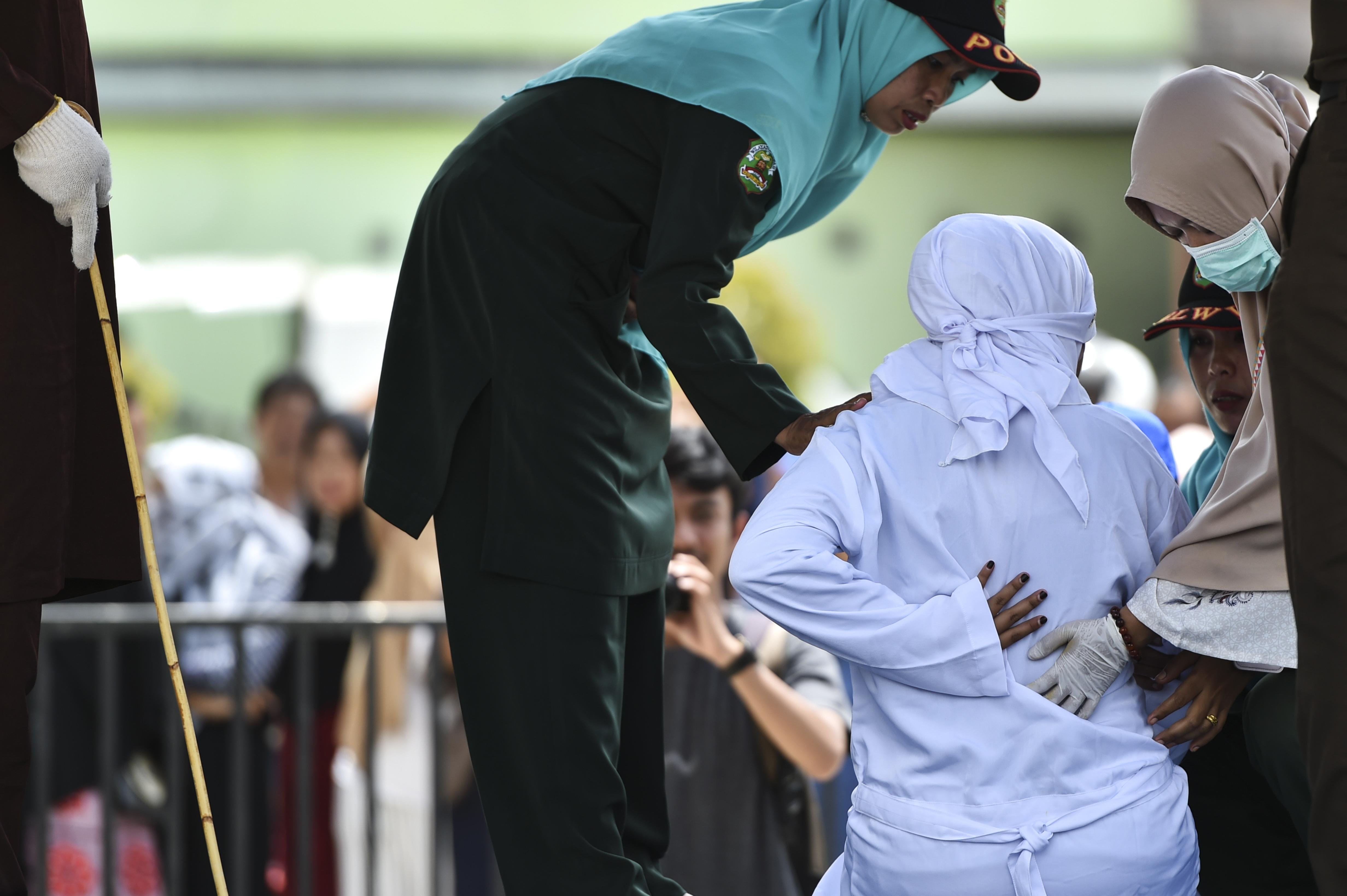 La policía de Sharia ayudó a una mujer (de blanco) después de que fue azotada en público en Banda Aceh, en la provincia de Aceh, el 1 de agosto de 2019. (Foto: AFP) 