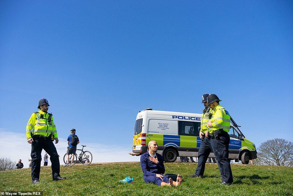 Police try to move on a sunbather yesterday on Primrose Hill, London, where some people flouted lockdown orders
