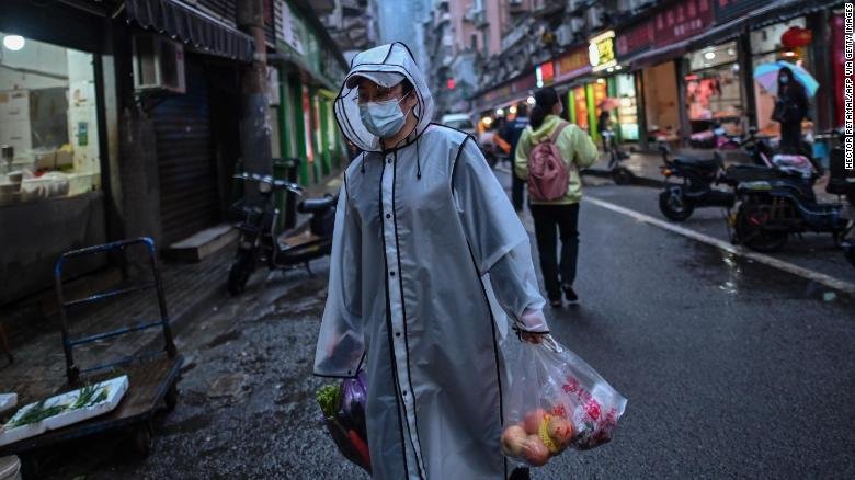 A person wearing a face mask as a preventive measure against the spread of the COVID-19 novel coronavirus carries groceries in a neighbourhood in Wuhan in China