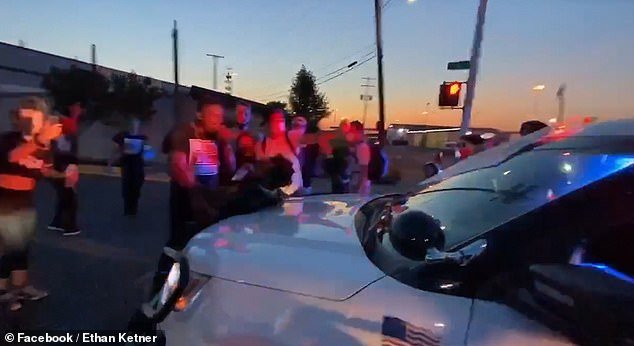In a clip - believed to be taken yesterday evening - a large crowd of protesters can be seen gathered around the front of a Detroit Police vehicle while chanting 
