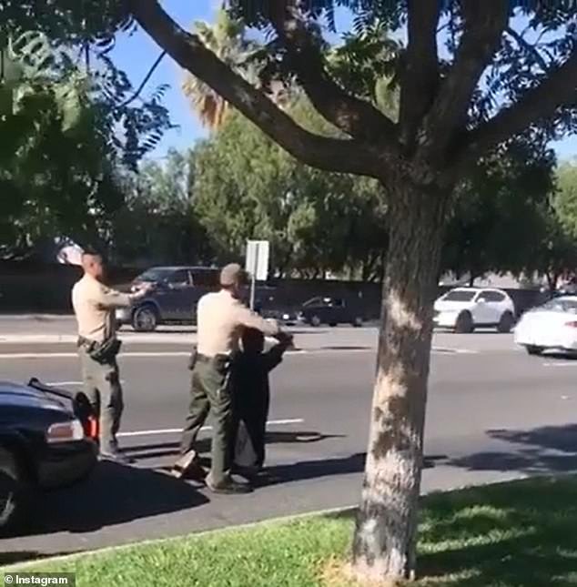 Two minutes into the clip, one of the three teens is seen getting down onto his knees in the middle of the road and is handcuffed by an officer