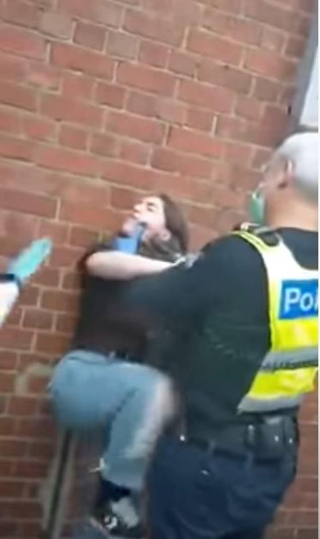 The officer can be seen pushing the woman against the wall as he grips her neck and head in his hands
