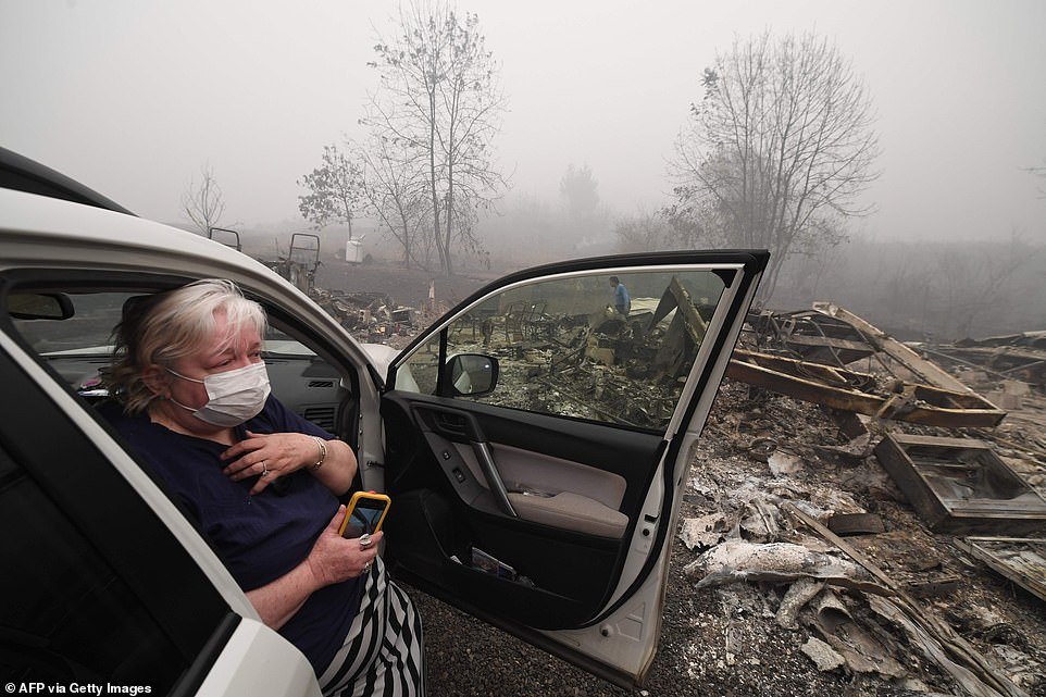 Margi Wyatt reacts after returning to find her mobile home destroyed by wildfire as her husband Marcelino Maceda (background) searches in the ruins in Estacada, Oregon, on Saturday