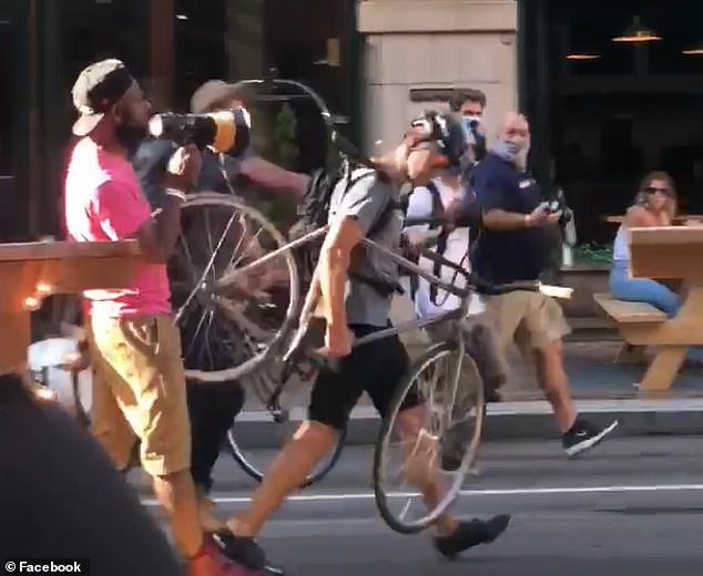 A man identified as Kenneth McDowell is seen shouting at a bicyclist through a megaphone during the confrontation outside Sienna Mercato