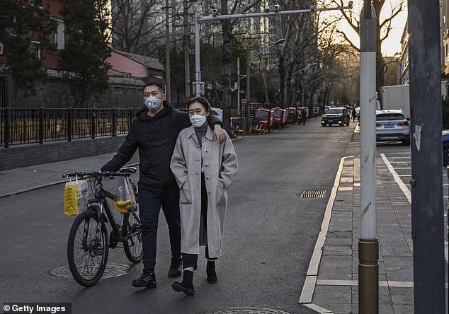 The event has sparked a heated discussion on Chinese social media after being reported this week, with many web users debating who should pay for blind dates. A Chinese couple is pictured wearing face masks as they walk through a quiet road in Beijing on March 19