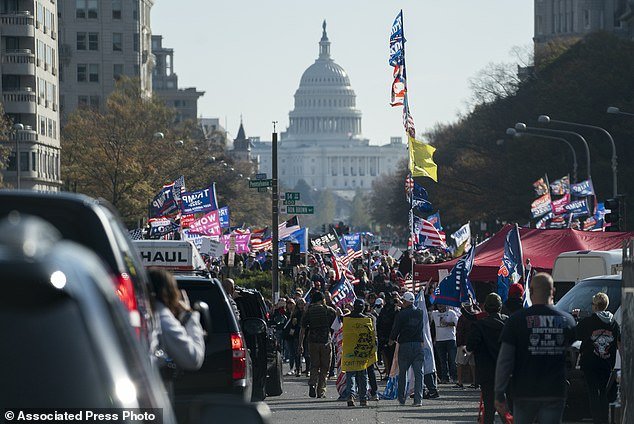 A motorcade carrying President Donald Trump drives by a group of supporters participating in a rally near the White House, Saturday, Nov. 14, 2020, in Washington