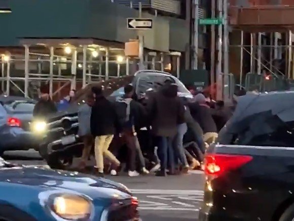 Amazing moment dozens of passers-by race to save woman trapped under SUV