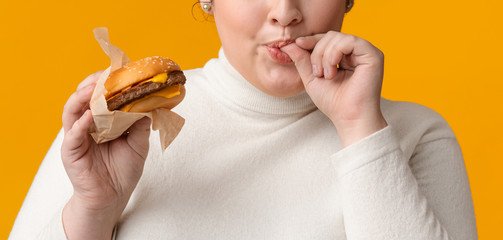 Young Obese Girl Eating Burger And Licking Fingers, Enjoying Fast Food Wall  Mural-Prostock-studio