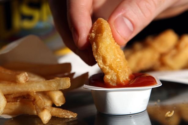 A chicken nugget being dunked in ketchup
