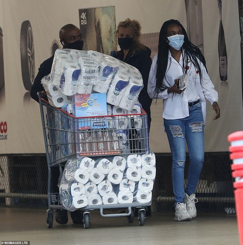 Panic-buyers are seen leaving a Costco store in Manchester today with a trolley full of toilet roll
