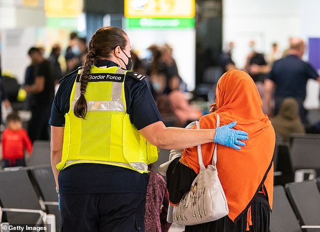 Afghan families who fled to Britain during the Taliban takeover of their country have asked to be sent back home. Pictured: Border Force staff assist a female evacuee as Afghan refugees arrive from Kabul at Heathrow Airport