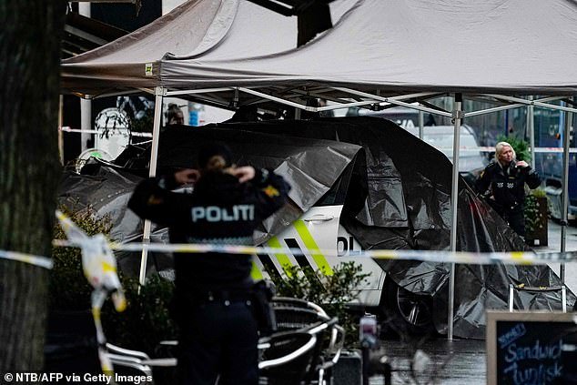 Police officers cover the police car that was involved in the attack in Norway