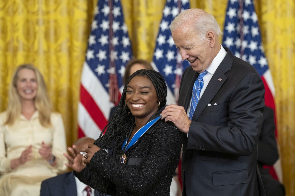 Simone Biles receives a medal from Joe Biden 